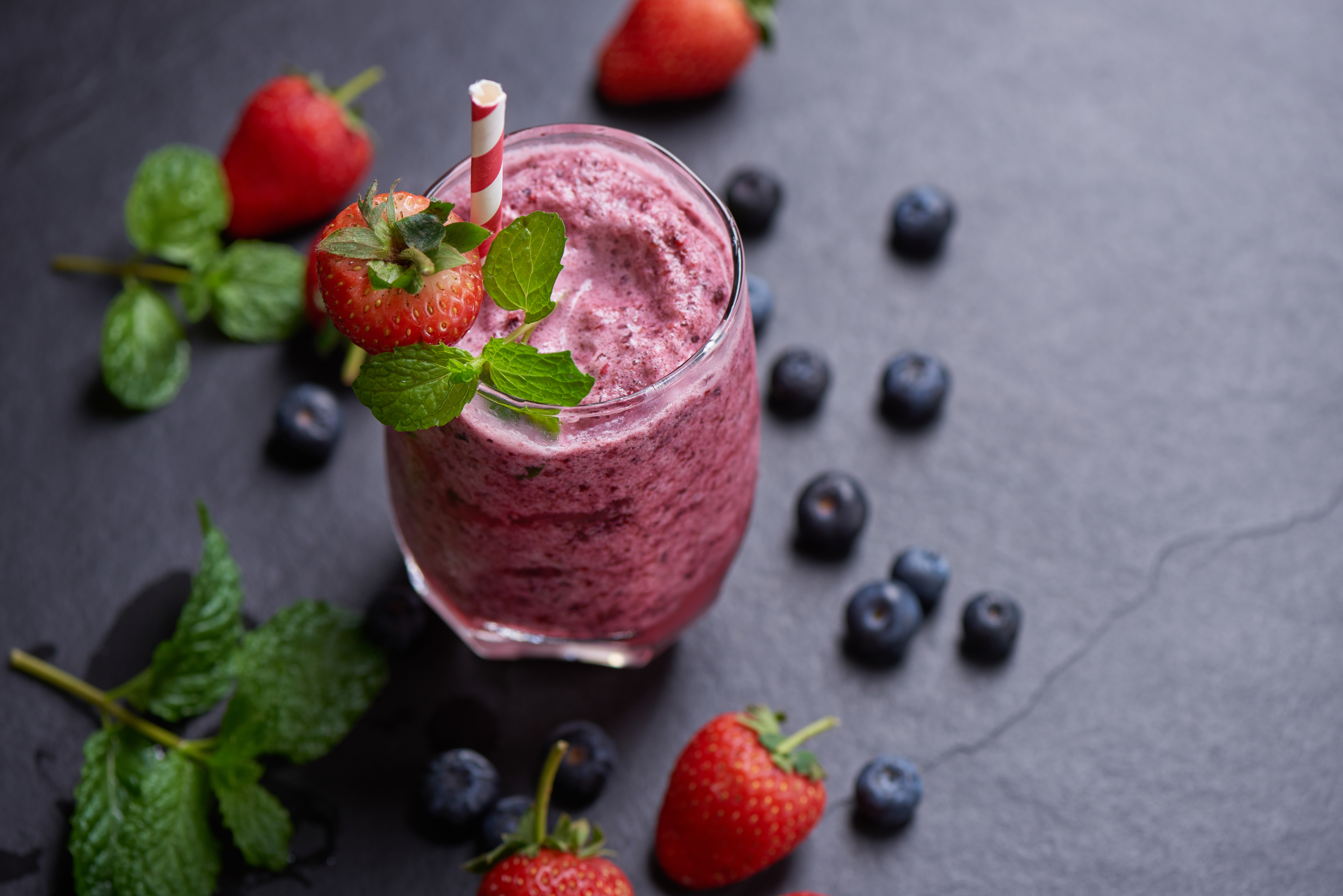 Delicious strawberry, mulberry and blueberry smoothie garnished Delicious strawberry, mulberry and blueberry smoothie garnished with fresh berries and mint in glass. soft focus. beautiful appetizer pink raspberries, well being and weight loss concept.